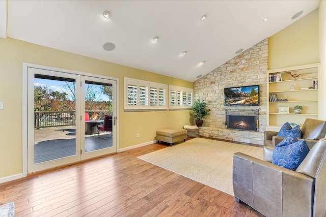 living room featuring a stone fireplace, high vaulted ceiling, and light wood-type flooring