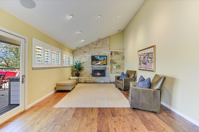 living room featuring a stone fireplace, high vaulted ceiling, and light wood-type flooring