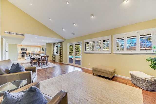 living room with high vaulted ceiling and light wood-type flooring