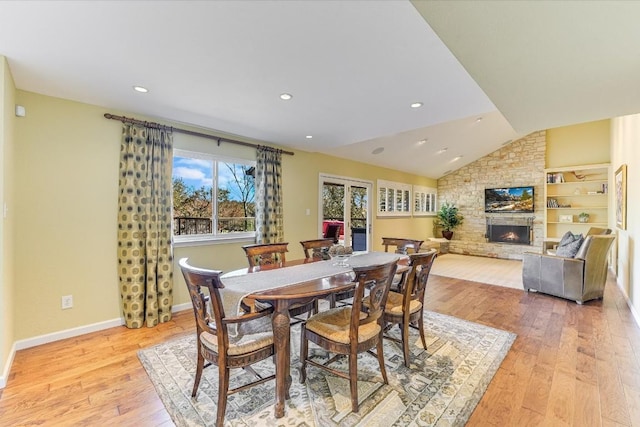 dining space with lofted ceiling, a fireplace, and light hardwood / wood-style flooring