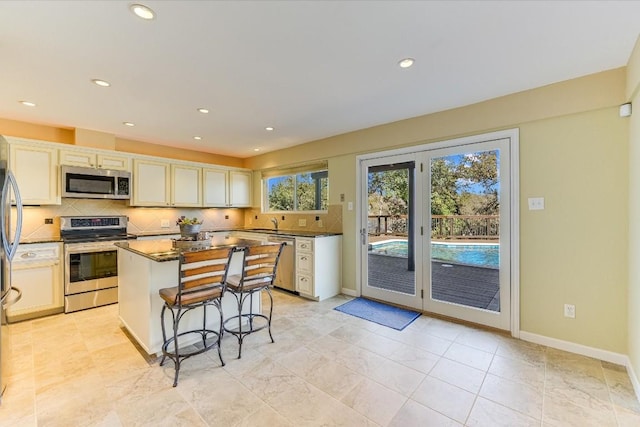 kitchen featuring a breakfast bar, tasteful backsplash, sink, a center island, and stainless steel appliances