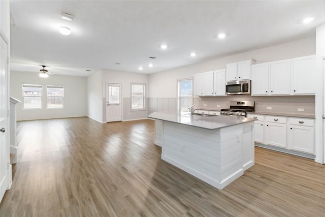 kitchen featuring white cabinetry, stainless steel appliances, sink, and a kitchen island with sink