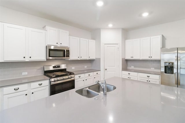 kitchen featuring sink, backsplash, white cabinets, and appliances with stainless steel finishes