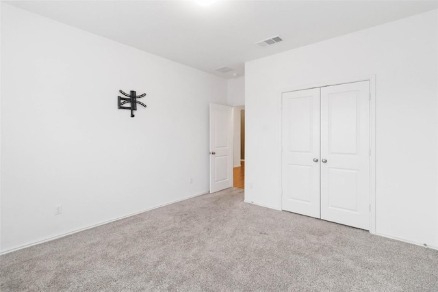 unfurnished bedroom featuring light colored carpet and a closet