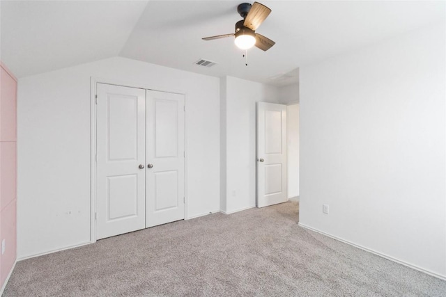 unfurnished bedroom featuring ceiling fan, a closet, vaulted ceiling, and light carpet