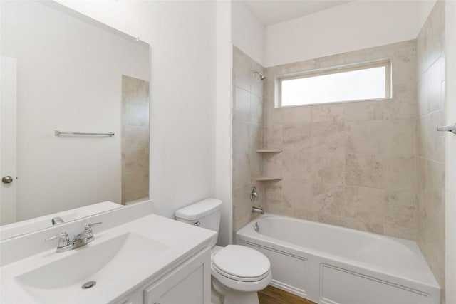 full bathroom with tiled shower / bath, vanity, and toilet