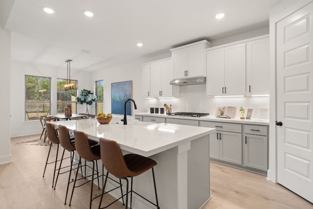 kitchen featuring stainless steel gas stovetop, sink, decorative light fixtures, and a kitchen island with sink