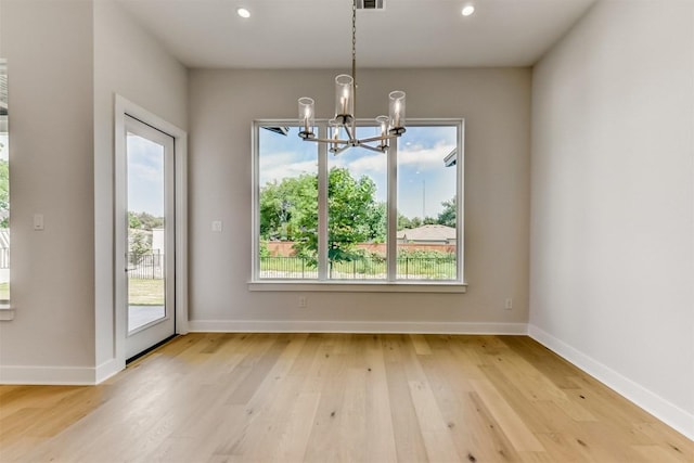 unfurnished dining area with a notable chandelier and light hardwood / wood-style flooring