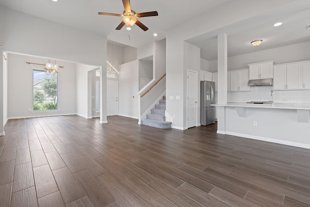 unfurnished living room with dark hardwood / wood-style flooring and ceiling fan with notable chandelier