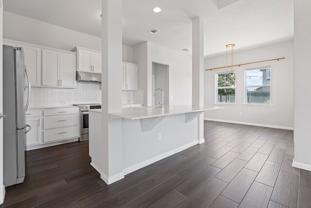 kitchen featuring dark hardwood / wood-style flooring, an island with sink, pendant lighting, stainless steel appliances, and white cabinets