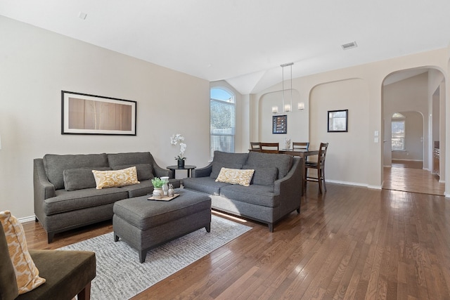 living room featuring wood-type flooring, lofted ceiling, and a notable chandelier