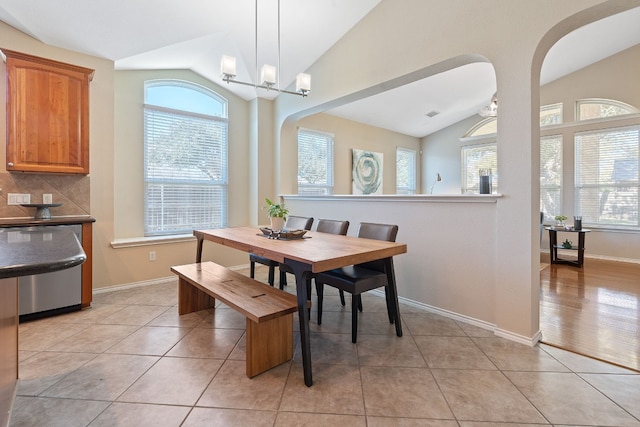 tiled dining area featuring lofted ceiling, plenty of natural light, and a chandelier