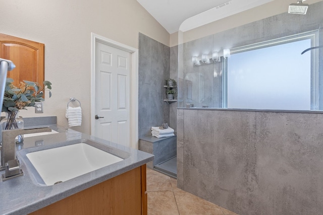 bathroom featuring tile patterned flooring, vaulted ceiling, sink, and a tile shower