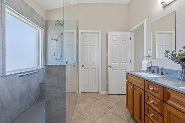 bathroom with vanity, vaulted ceiling, a tile shower, and tile patterned floors