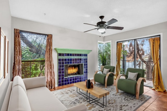 living area with a tiled fireplace, tile patterned flooring, and ceiling fan