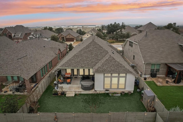 rear view of property with a shingled roof, a patio, a fenced backyard, a residential view, and a yard