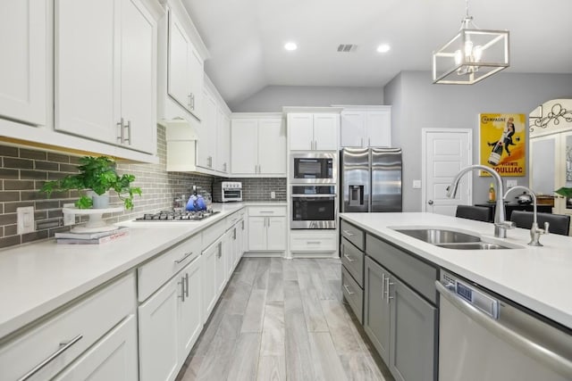 kitchen with appliances with stainless steel finishes, white cabinets, a sink, and light countertops