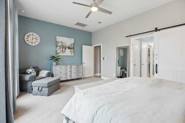 bedroom with light carpet, a barn door, and ceiling fan