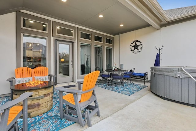 view of patio / terrace with an outdoor fire pit, outdoor dining area, and a hot tub