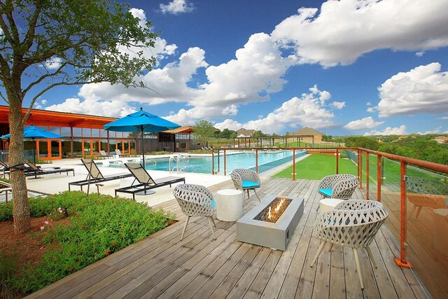 view of pool featuring a wooden deck and an outdoor fire pit