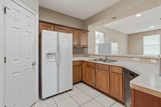 kitchen featuring sink, light tile patterned floors, white refrigerator, dishwasher, and white fridge with ice dispenser