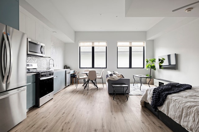 bedroom featuring stainless steel fridge, sink, and light wood-type flooring