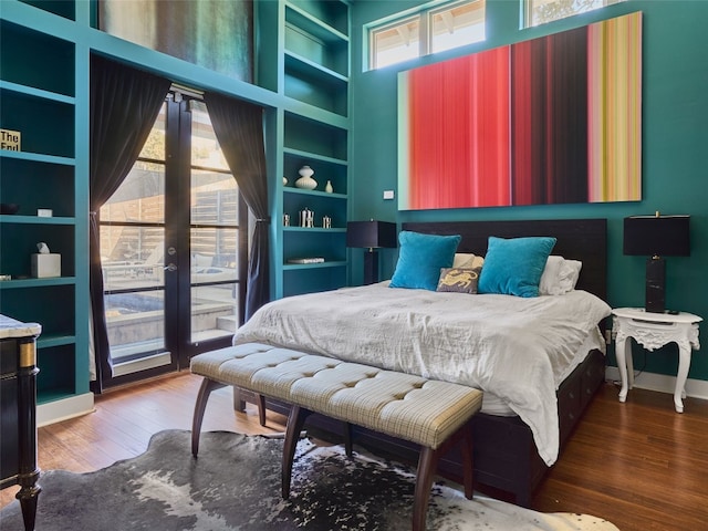 bedroom with french doors, wood-type flooring, and a high ceiling