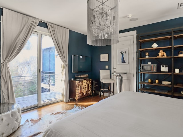 bedroom with access to exterior, a notable chandelier, and wood-type flooring