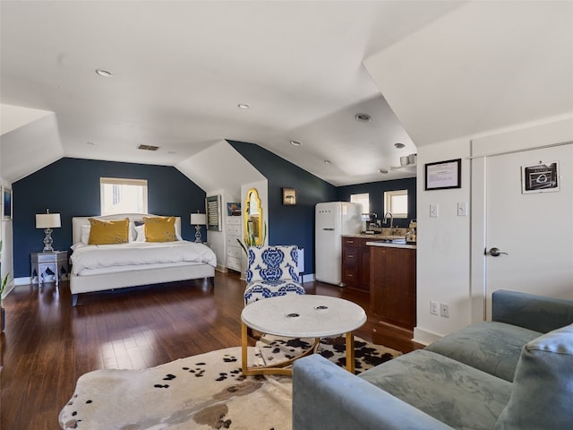 bedroom with lofted ceiling, hardwood / wood-style floors, and white fridge