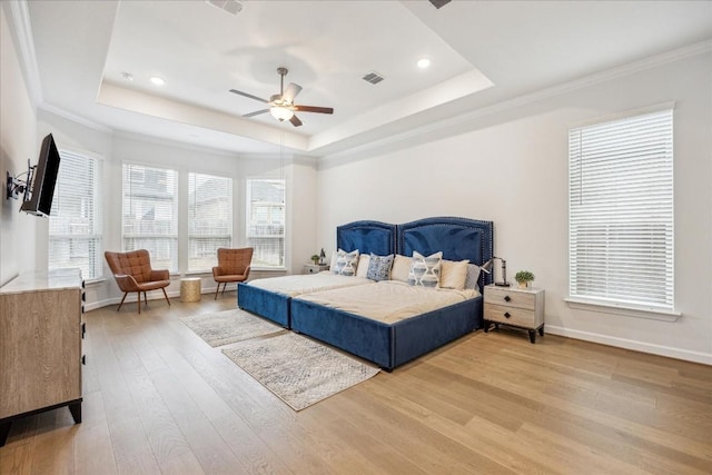 bedroom with ornamental molding, a raised ceiling, ceiling fan, and light wood-type flooring