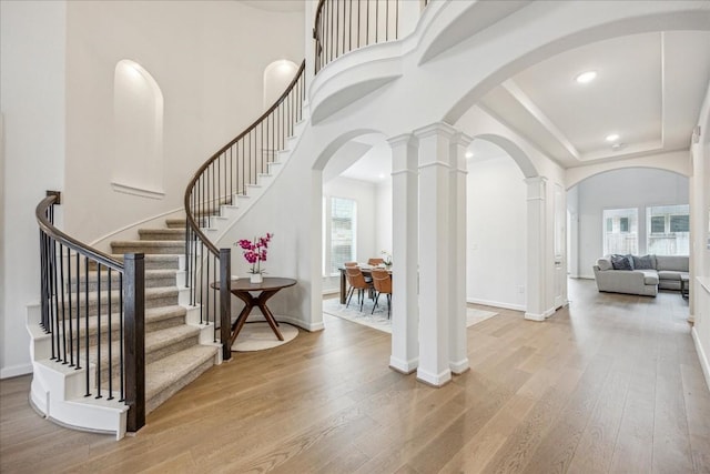 entrance foyer featuring decorative columns, a high ceiling, and light wood-type flooring