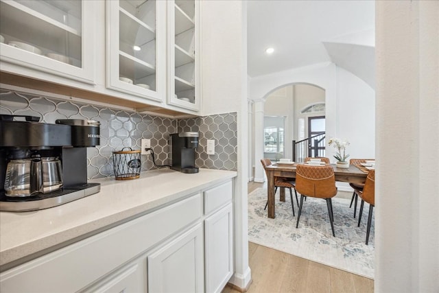 kitchen featuring white cabinetry, ornamental molding, decorative backsplash, and light wood-type flooring