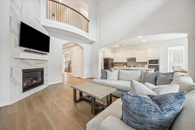 living room with a towering ceiling, a fireplace, and light hardwood / wood-style floors