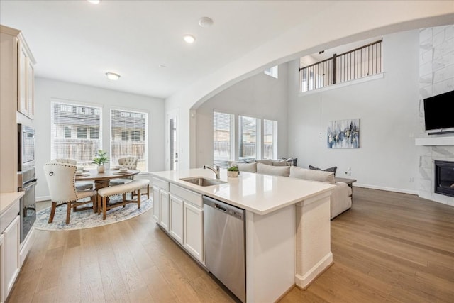 kitchen featuring sink, stainless steel appliances, a fireplace, a kitchen island with sink, and white cabinets