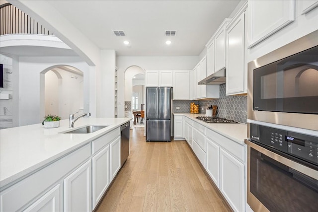 kitchen with stainless steel appliances, backsplash, white cabinets, and light hardwood / wood-style floors