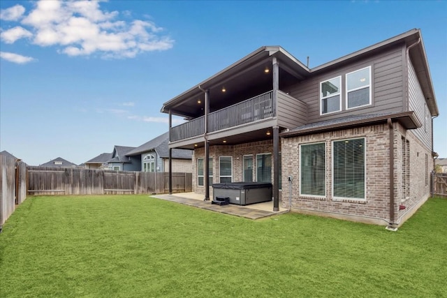 rear view of property with a hot tub, a patio, a balcony, and a lawn