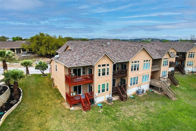 rear view of property with central AC unit and a lawn