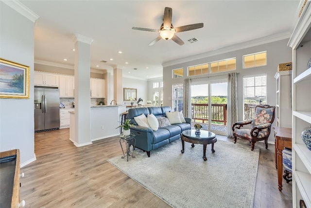 living room featuring ornamental molding, ceiling fan, and light wood-type flooring