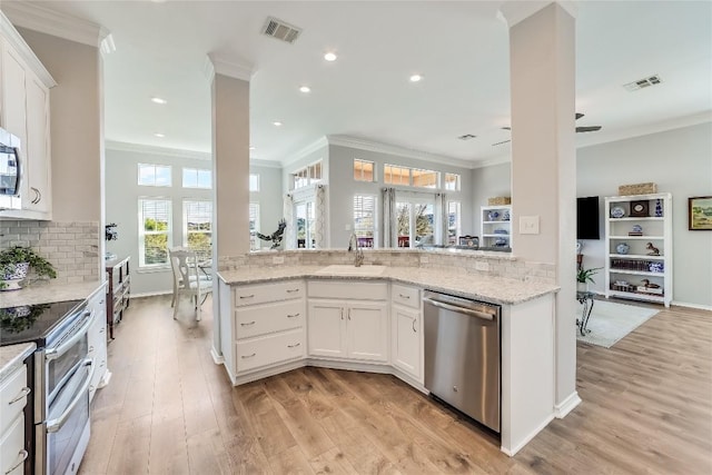 kitchen featuring white cabinetry, sink, ornamental molding, light stone counters, and stainless steel appliances