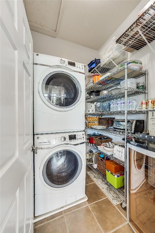 laundry area with stacked washer and dryer and dark tile patterned floors