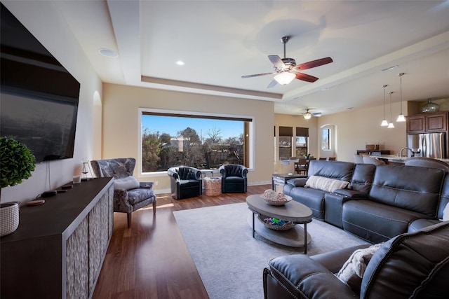 living room with sink, dark hardwood / wood-style floors, a raised ceiling, and ceiling fan