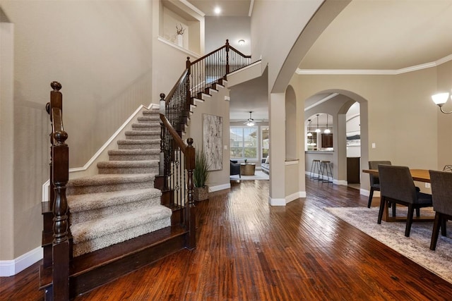 entryway featuring dark hardwood / wood-style flooring, ornamental molding, and a high ceiling