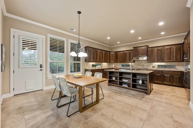 dining area featuring crown molding, sink, and light tile patterned floors