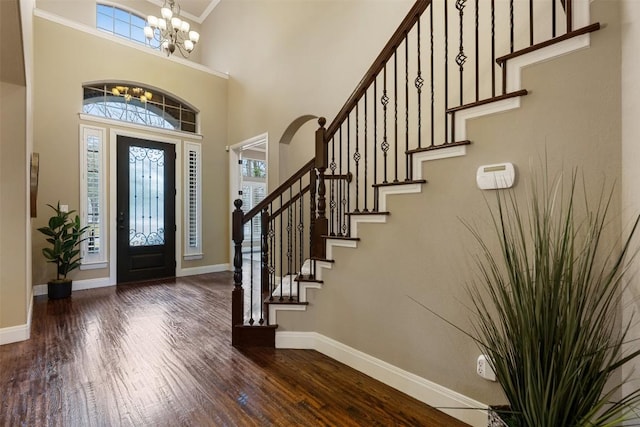 foyer entrance with a high ceiling, a notable chandelier, and dark hardwood / wood-style flooring