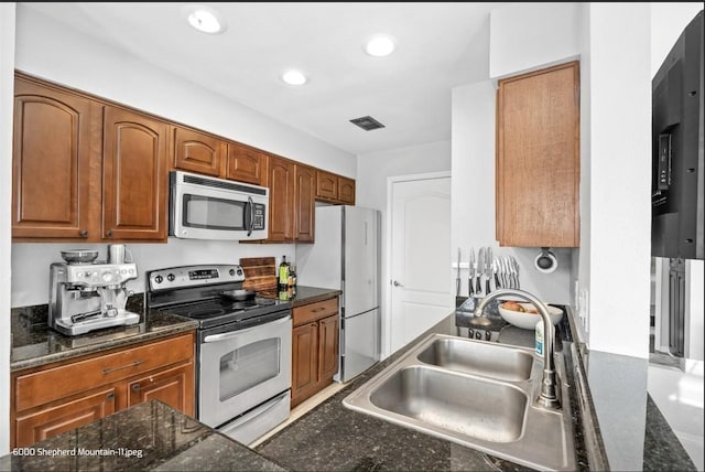 kitchen featuring stainless steel appliances, sink, and dark stone counters