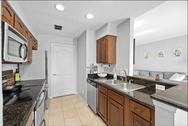 kitchen with light tile patterned flooring, stainless steel appliances, sink, and dark stone counters