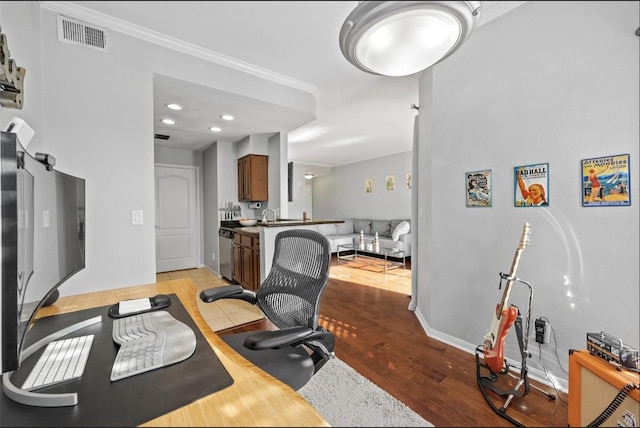 home office with crown molding and light hardwood / wood-style floors