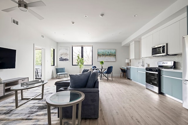 living room with sink, light hardwood / wood-style flooring, and ceiling fan