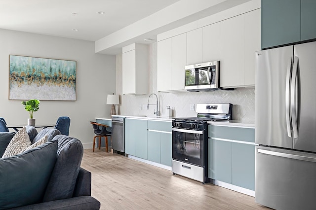 kitchen with white cabinetry, decorative backsplash, stainless steel appliances, and light hardwood / wood-style floors