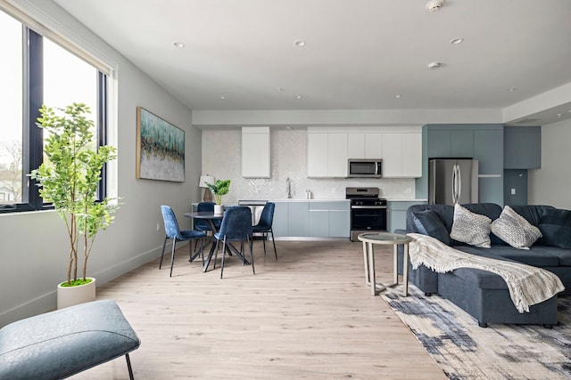 kitchen featuring sink, tasteful backsplash, light wood-type flooring, stainless steel appliances, and white cabinets